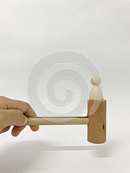 Hand holding wooden hammer with wooden human on the top