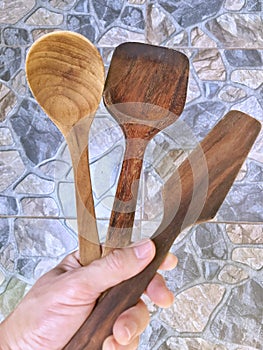 Hand holding wooden ladle and spatula