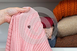 Hand holding woolen knitted cloth with hole