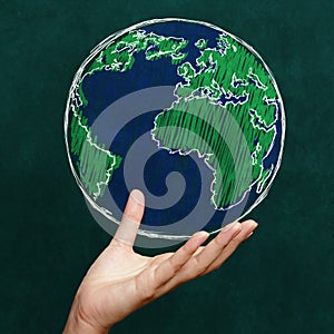 Hand holding world on chalkboard