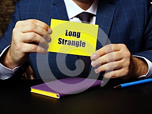 Hand holding yellow business card with phrase Long Strangle . Close-up shot