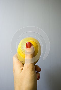 Hand holding yellow lemon