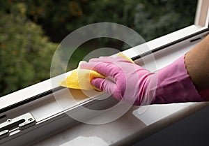 Hand holding a yellow microfiber cloth to clean dust on a window rail