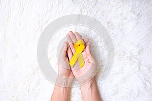 Hand holding Yellow Ribbon on white background for supporting people living and illness. September Suicide prevention day,