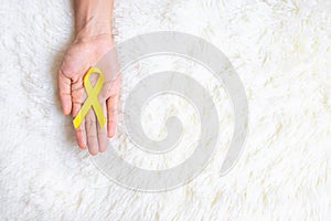 Hand holding Yellow Ribbon on white background for supporting people living and illness. September Suicide prevention day,