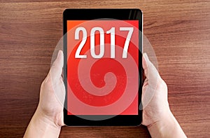 Hand holdling tablet with 2017 year number on screen on wood tab