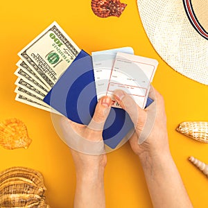 Hand holds airline boarding pass for summer travek and vacation concept background with passport, money and seashells