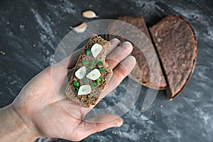 Hand holds bitten sandwich artisan bread with onion chives and garlic, degustation of rye sourdough bread