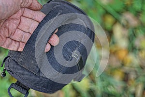 Hand holds a black fabric handle on the dirty bag