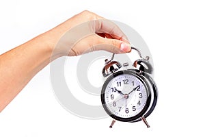 Hand holds a black shiny alarm clock on white background