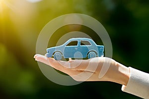 Hand holds blue car toy, symbolizing insurance, financial planning
