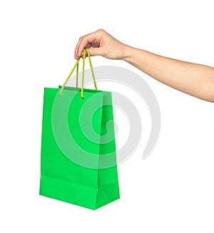 The hand holds a bright green bag for shopping