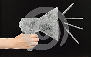 Hand holds chalk megaphone drawn on blackboard