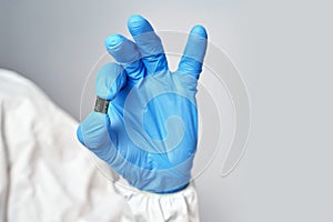 Hand holds chip compenent.. Microchip close-up. Implantation to humanity