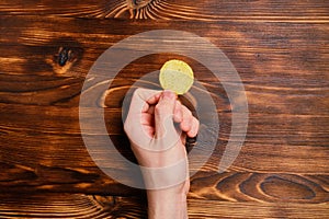 Hand holds chips on a wooden deified background. Top view