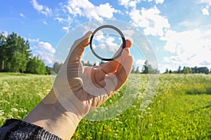 Hand holds a circular polarizer filter on field background. photo