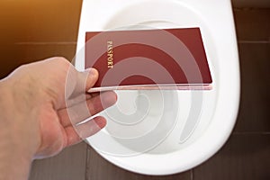 Hand holds the citizen`s passport over the toilet, throw out his passport. Concept - change of citizenship, loss of passport, pol