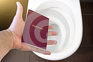 Hand holds the citizen`s passport over the toilet, throw out his passport. Concept - change of citizenship, loss of passport, pol