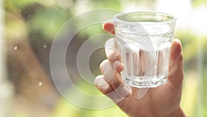 Hand holds clear water in glass . hand holding A clear glass of clean mineral water . Concept of environment protection, healthy