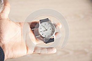 Hand holds clock isolated on wooden background