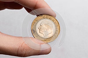 A hand holds a coin of one Turkish lira with a portrait of Mustafa Kemal Ataturk on a white background close-up