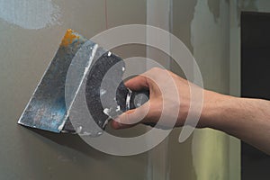 Hand holds construction spatula with putty. trowel with spackling. renovation process
