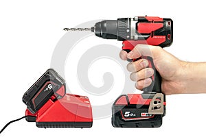 A hand holds a cordless drill on a white isolated background, side view. A set of a cordless drill and a charger that