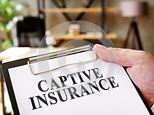 Hand holds document Captive insurance about insurance.