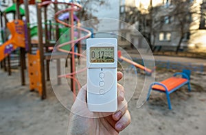 A hand holds a dosimeter radiometer device for measuring radiation