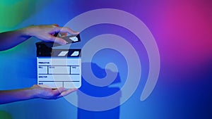 Hand holds empty film making clapperboard on color background in studio