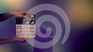 Hand holds empty film making clapperboard on color background in studio