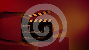 Hand holds empty film making clapperboard on color background in studio