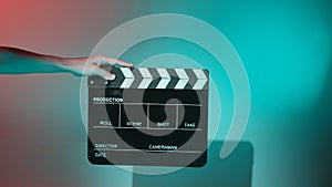 Hand holds empty film making clapperboard on color background in studio