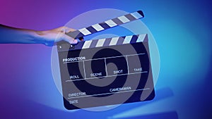 Hand holds empty film making clapperboard on color background in studio