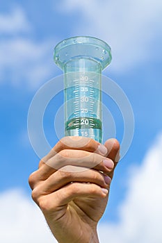 Hand holds filled water meter up in sky