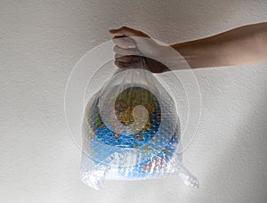 Hand holds a globe wrapped in plastic