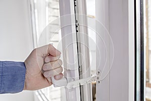 The hand holds the handle of window with restrictor