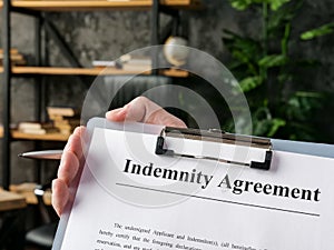 Hand holds indemnity agreement for signing in the office.