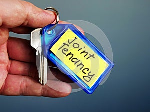 Hand holds key with Joint Tenancy inscription photo
