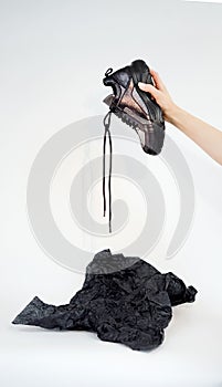Hand holds a leather stylish sneaker with untied laces on a white background close-up