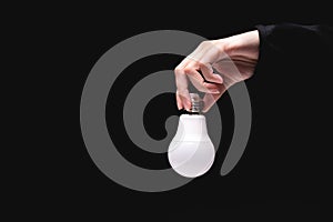 hand holds an LED light bulb on a black background. Using an economical and environmentally friendly light bulb