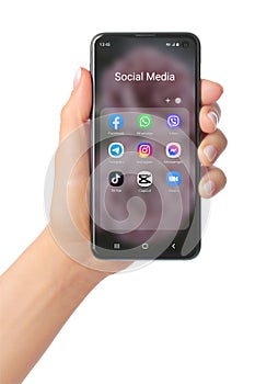 Hand holds mobile phone with icons of popular social media mobile apps on its screen, such as: Facebook, Messenger, Whatsapp,