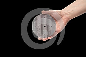 A hand holds a multilayer semiconductor silicon wafer with a microcircuit chip of a powerful Darlington transistor isolated on a