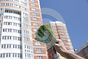 Hand holds a new Russian banknote two hundred rubles on the background of a big building and blue sky. Cash paper money