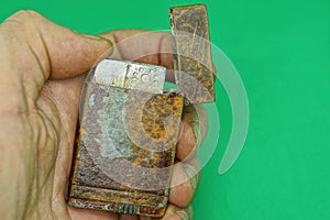 Hand holds an old brown open shabby metal lighter