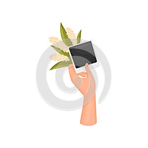 Hand holds a photo card of a poloroid and a bouquet of white inflorescences. Vector illustration on white background.