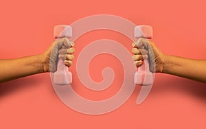 Hand holds a pink dumbbell isolated on a pink background. Equipment for training at home. Fitness and activity. sport