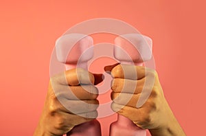 Hand holds a pink dumbbell isolated on a pink background. Equipment for training at home. Fitness and activity. sport