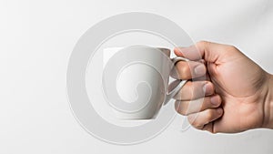 A hand holds a plain white ceramic mug against a neutral background