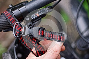 Hand holds a red black harness with a closed plastic carabiner